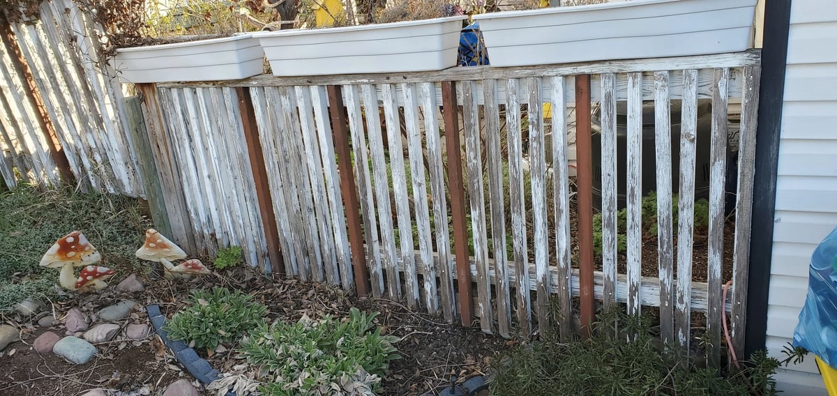 Before: Grey, peeling pickets and red-brown posts, with the planter boxes above, all painted white.