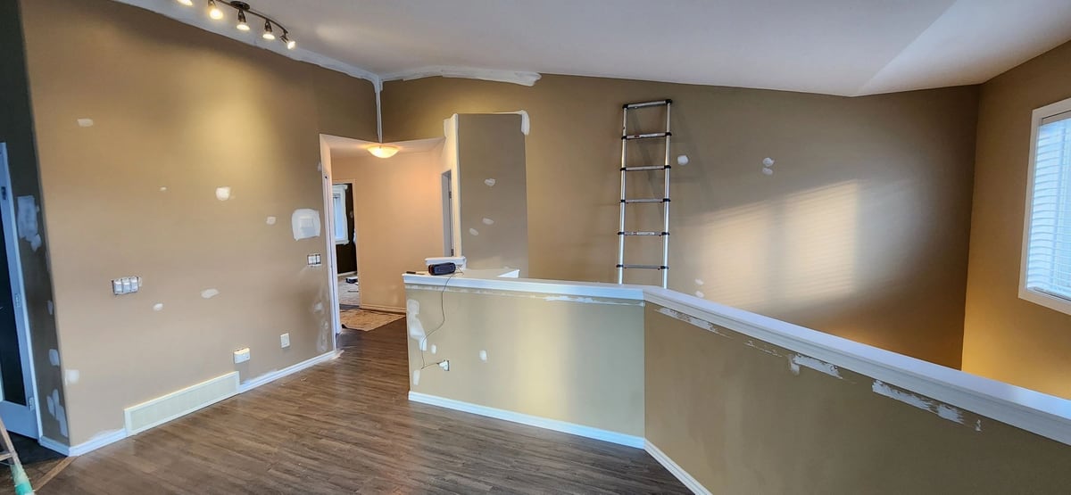 Before: Tan walls dotted with patches, finished into a clean white landing and hallway.