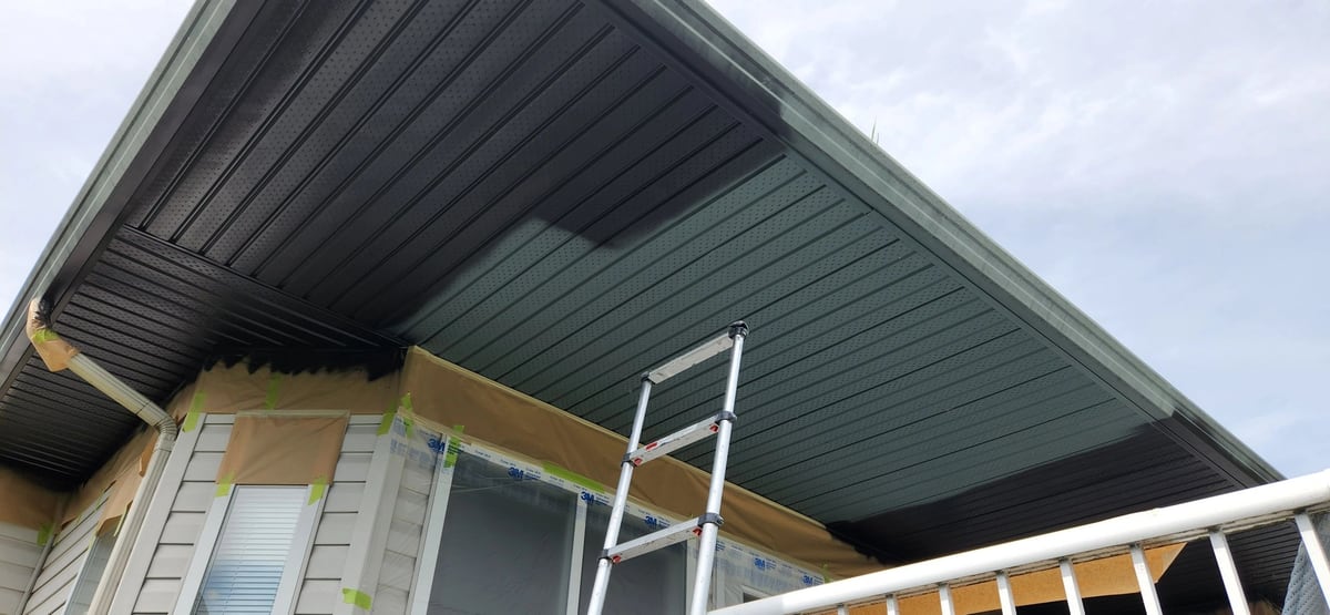 After: Soffits rolled dark brown while masking paper protects the siding and windows below.